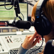 Rear view of female dj working in front of a microphone on the radio